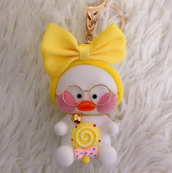 Брелок Lalafanfan Белая утка с желтым бантом держит леденец на палочке 10 см