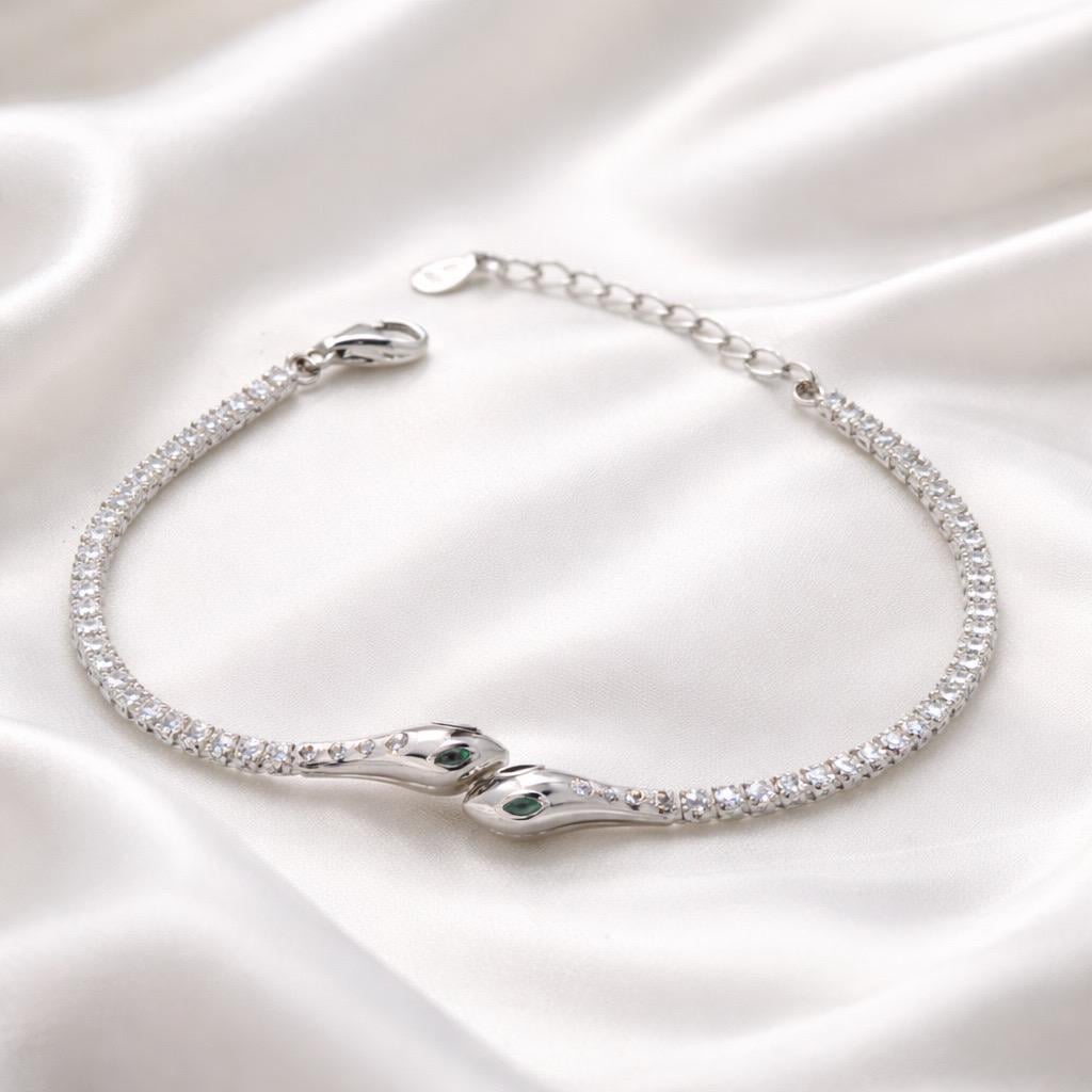 Браслет серебрянный с прозрачными фианитами круглой формы и центральным элементом в виде змей с зелеными вставками р. 17-20 см